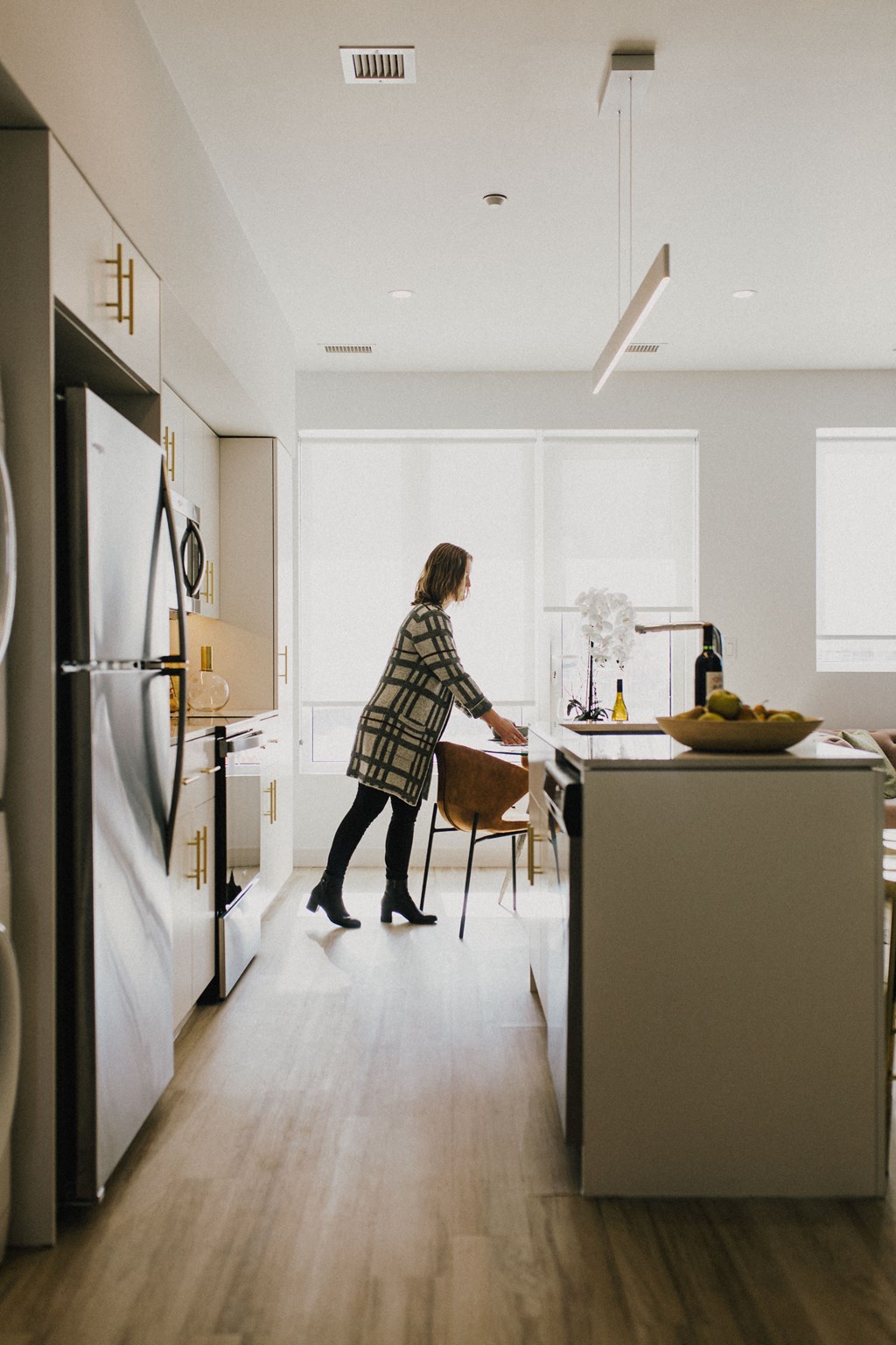 a woman in a kitchen with a table and a refrigerator