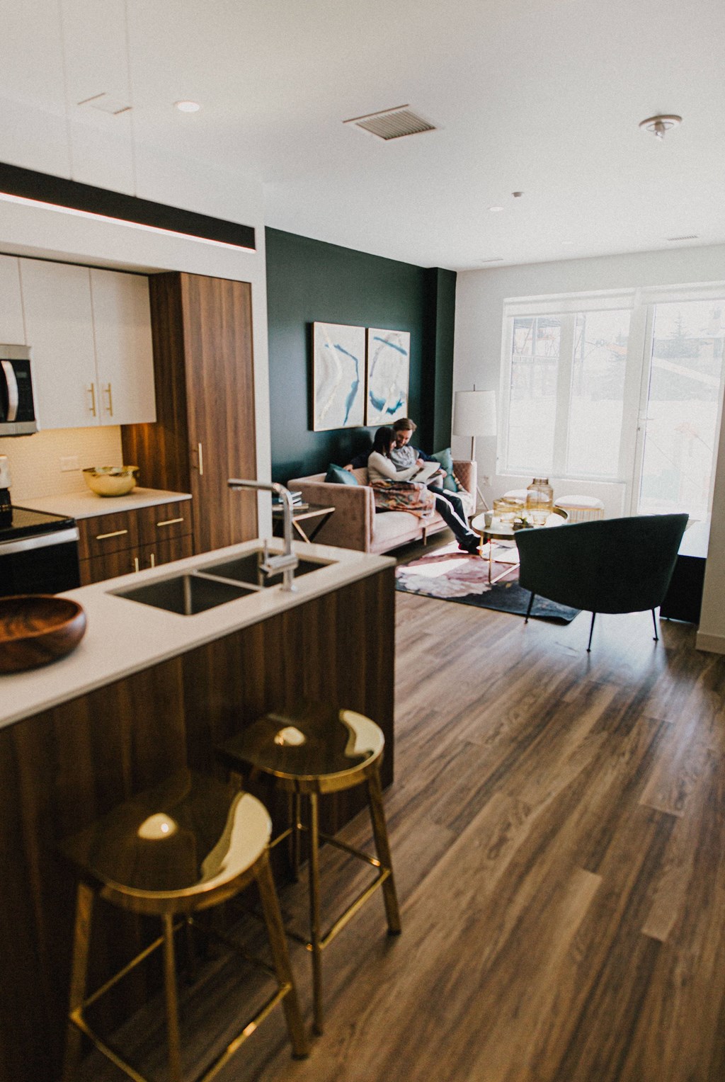 A kitchen with a woman sitting on a couch.
