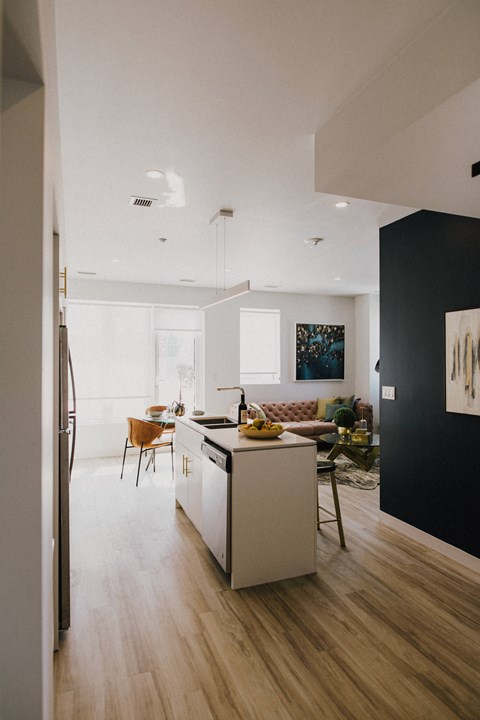 a kitchen and living room with white walls and wooden floors