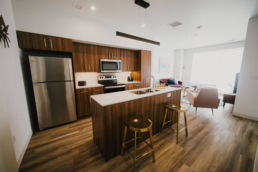 a kitchen and living room with wooden floors and a stainless steel refrigerator