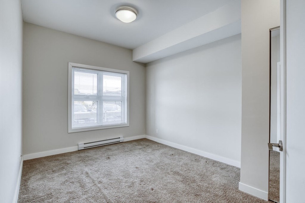 an empty room with a window and carpet