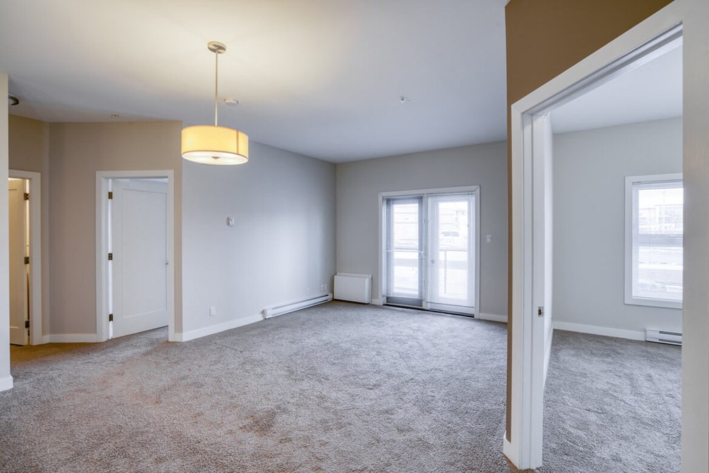 an empty living room with two doors and a ceiling lamp