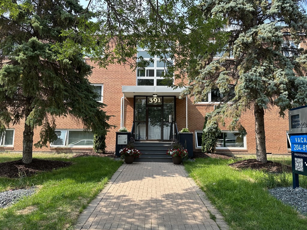 a brick building with a black door and a tree in front of it