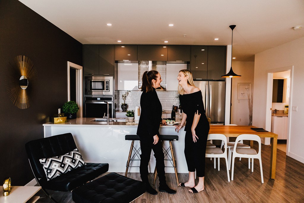 two women standing in a living room in a kitchen