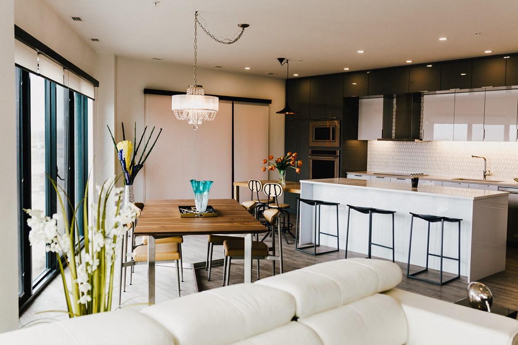 a living room and kitchen with white furniture and a wooden table