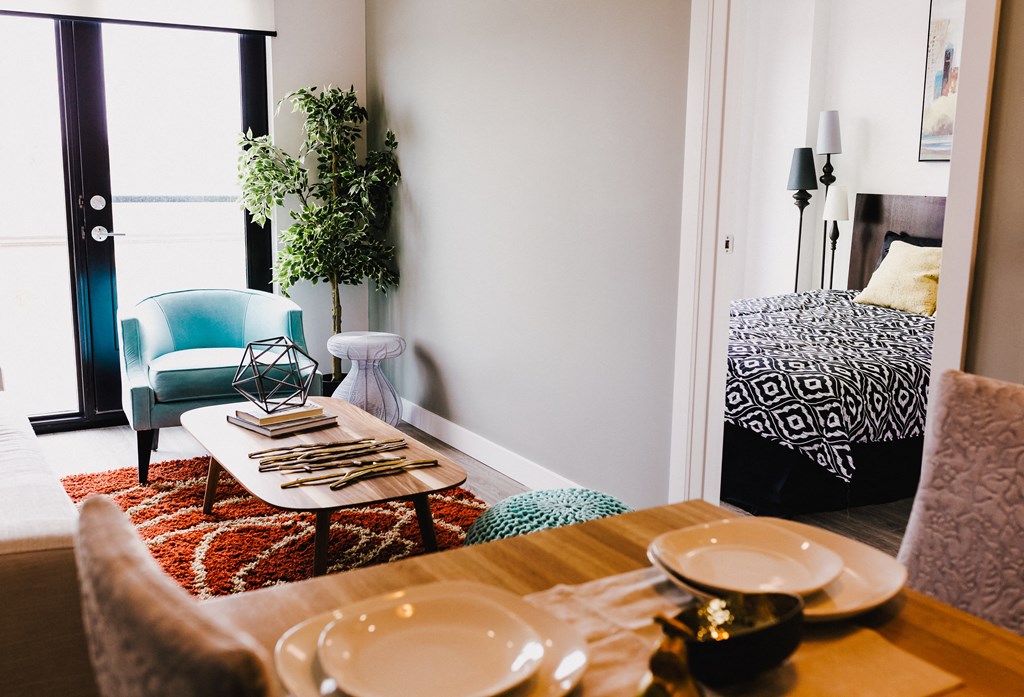 a living room with a dining table and a bed in the background