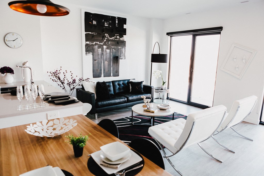 a living room and dining room with white furniture and a black leather couch