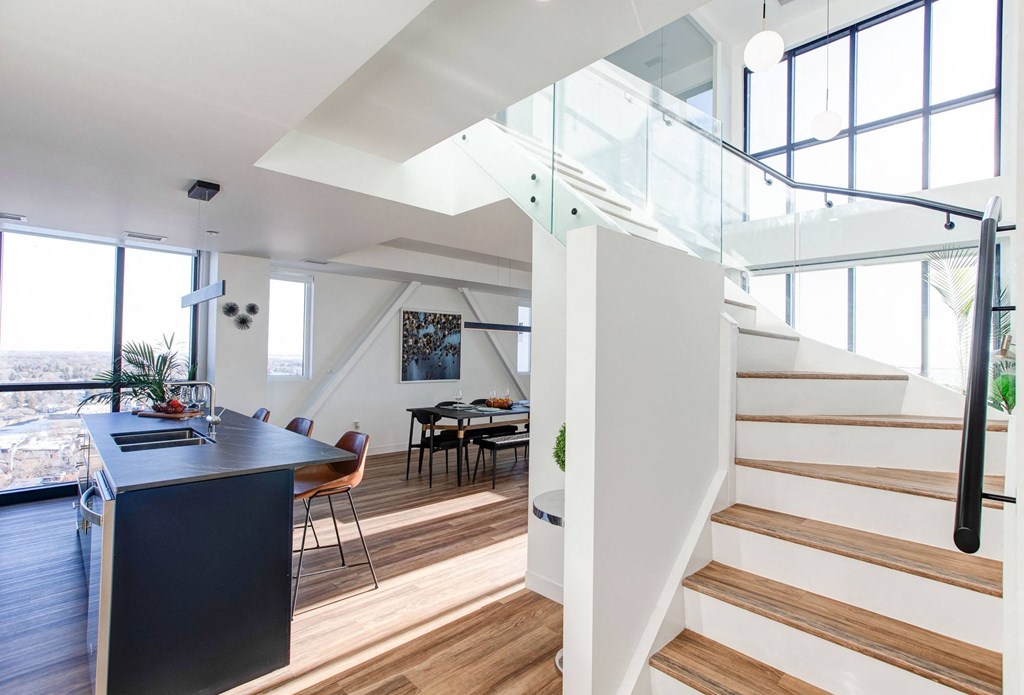 a living room with a staircase and a table and a kitchen