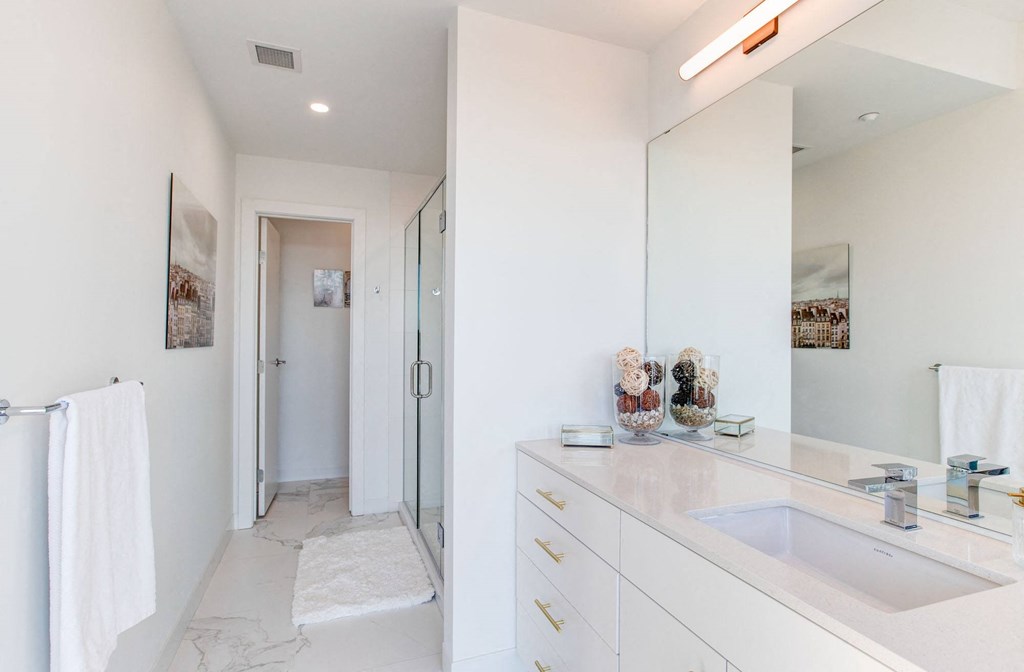 a white bathroom with a sink and a shower