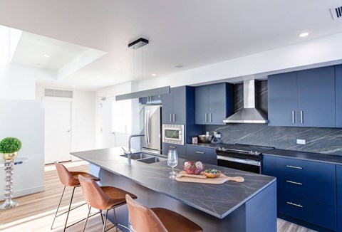 A modern kitchen with blue cabinets and a grey countertop.