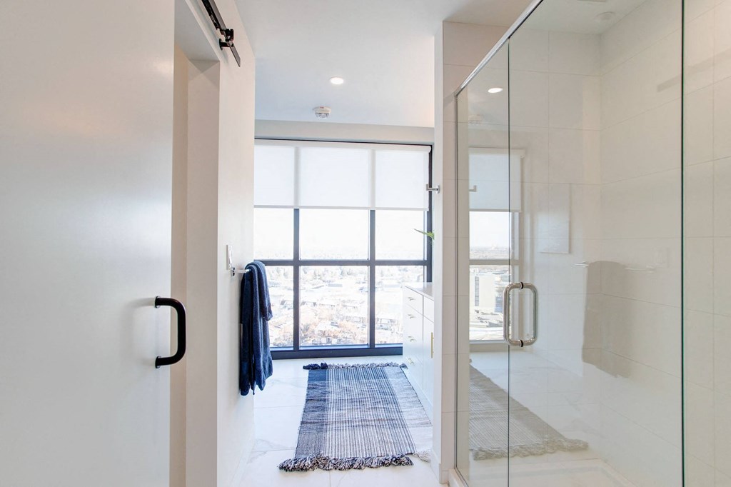 a bathroom with a glass shower and a blue rug