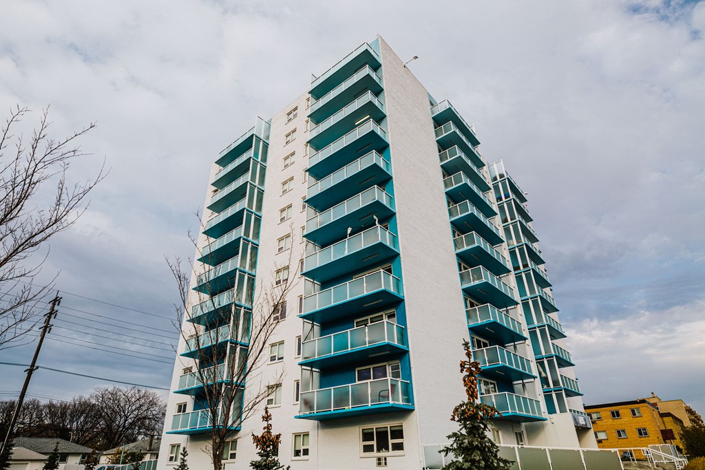 a tall building with green balconies and a cloudy sky