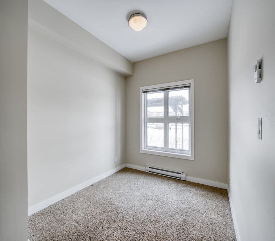 an empty room with a window and carpet