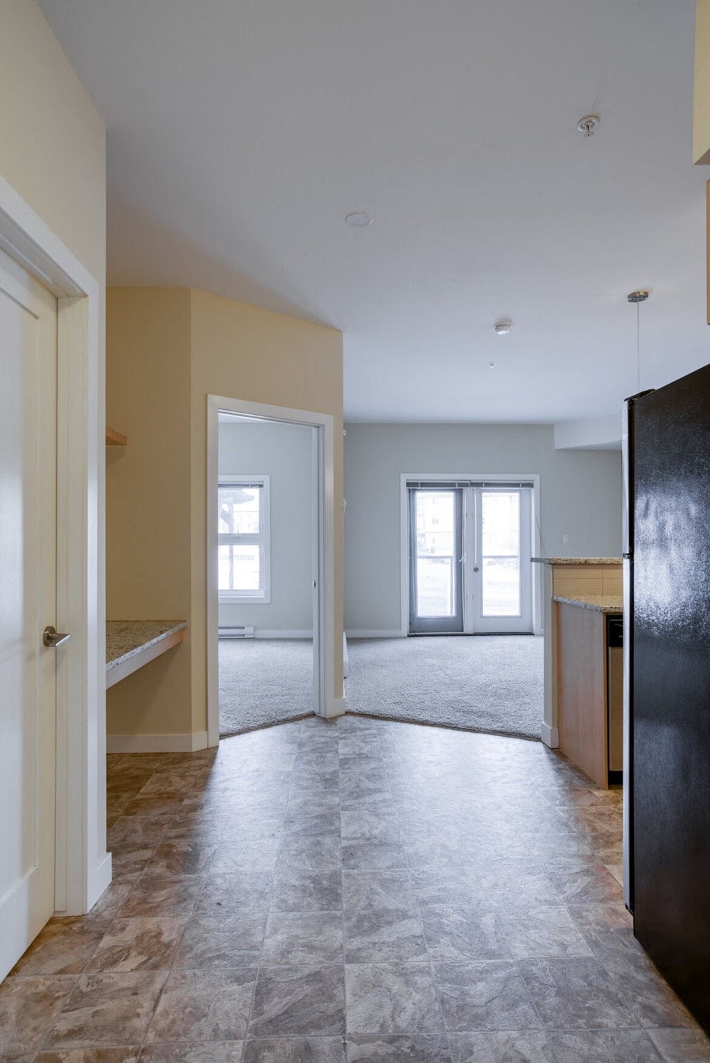 an empty living room and kitchen with the door open