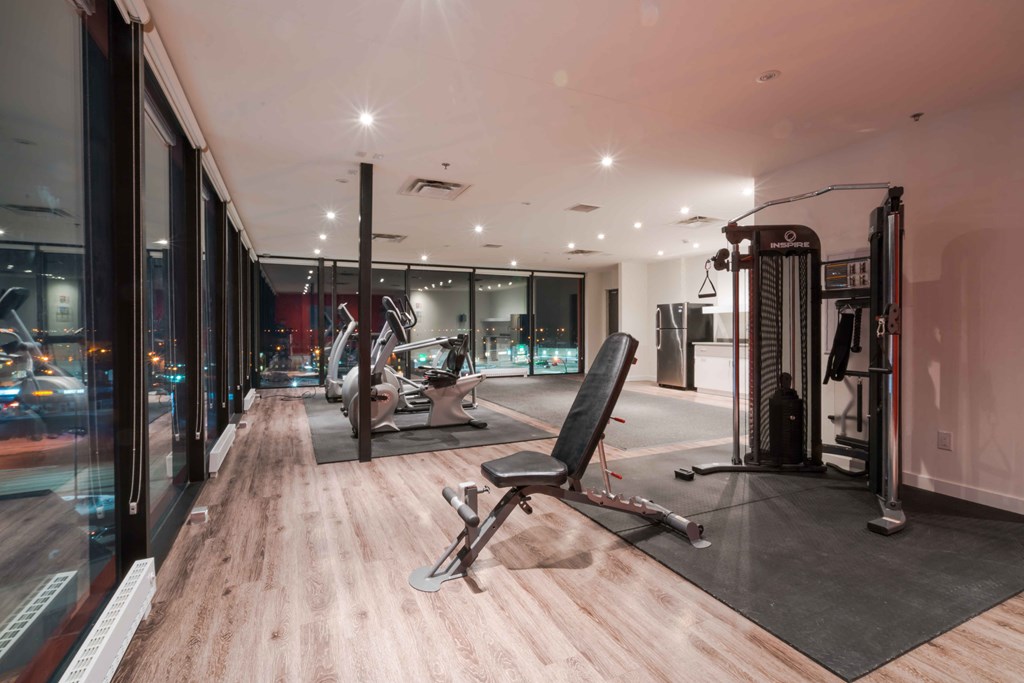 a gym with glass walls and a workout area with chairs and equipment