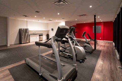 a gym with exercise equipment and a red wall
