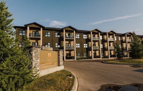 an apartment building with a sign and trees in the foreground