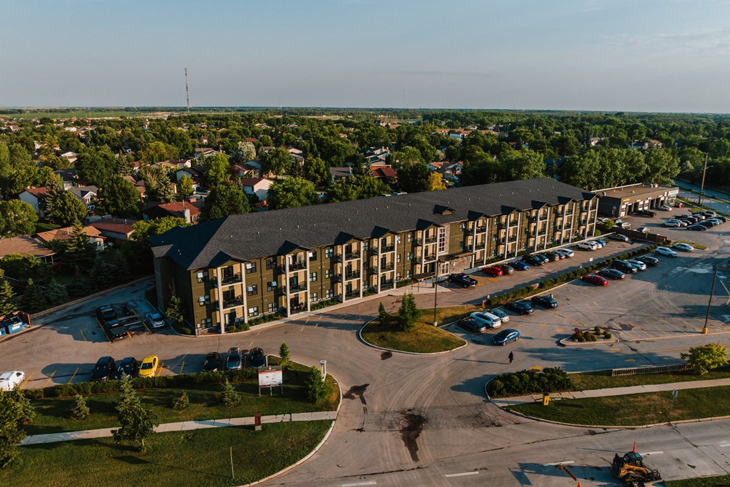 an aerial view of a large apartment complex with a parking lot and trees