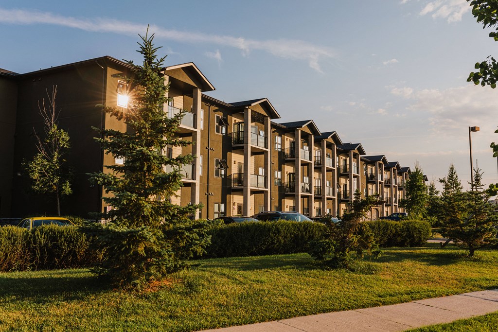 an apartment complex with a sidewalk and trees in the foreground