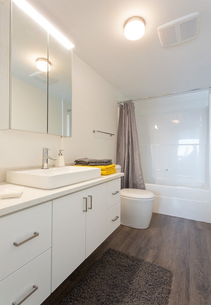 a bathroom with white cabinetry and a white toilet next to a white bathtub