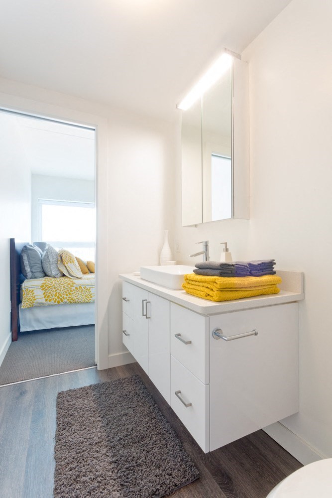 a bathroom with white cabinets and a white sink with a mirror above it