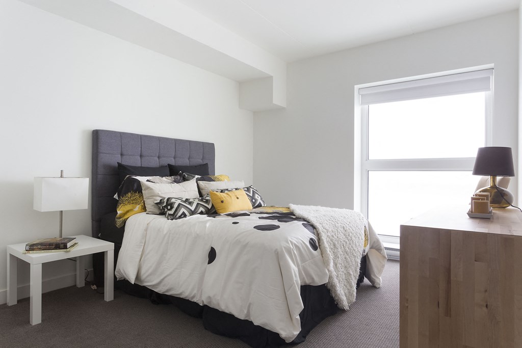 a bedroom with white walls and a large bed with black and yellow bedding