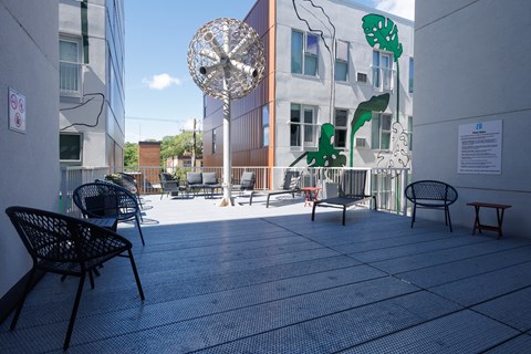 A patio with chairs and a table with a sign on the wall.