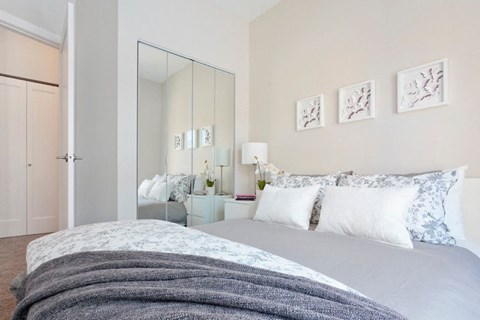 a white bedroom with a bed and a mirror