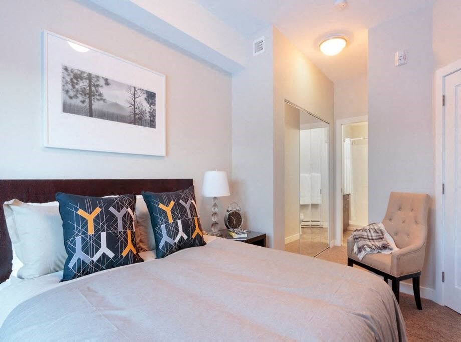 a bedroom with a bed and a chair and a mirror