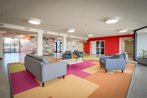 a lobby with couches and chairs on a colorful rug