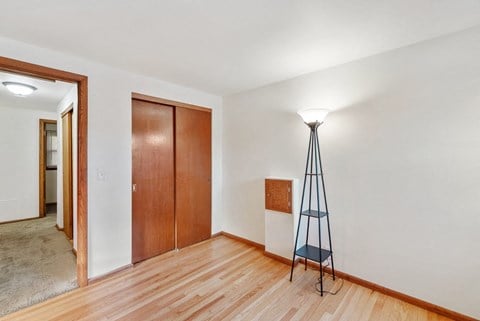 a living room with a tripod lamp and a door to a bedroom