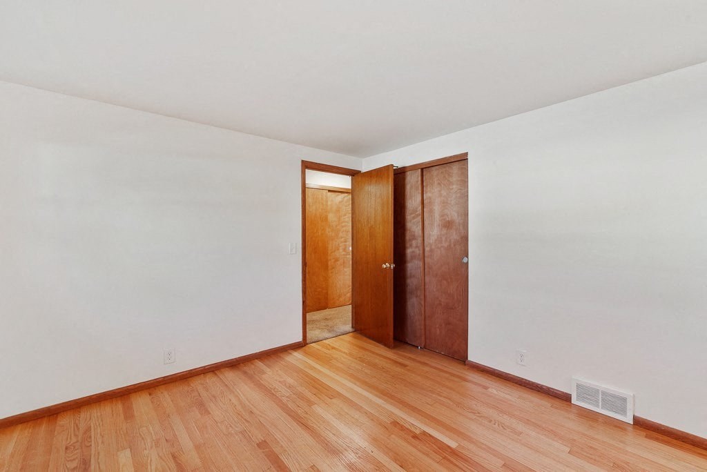 a living room with white walls and wooden floors and a wooden door