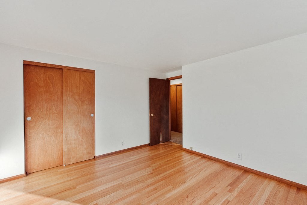 an empty living room with wood floors and a wooden door