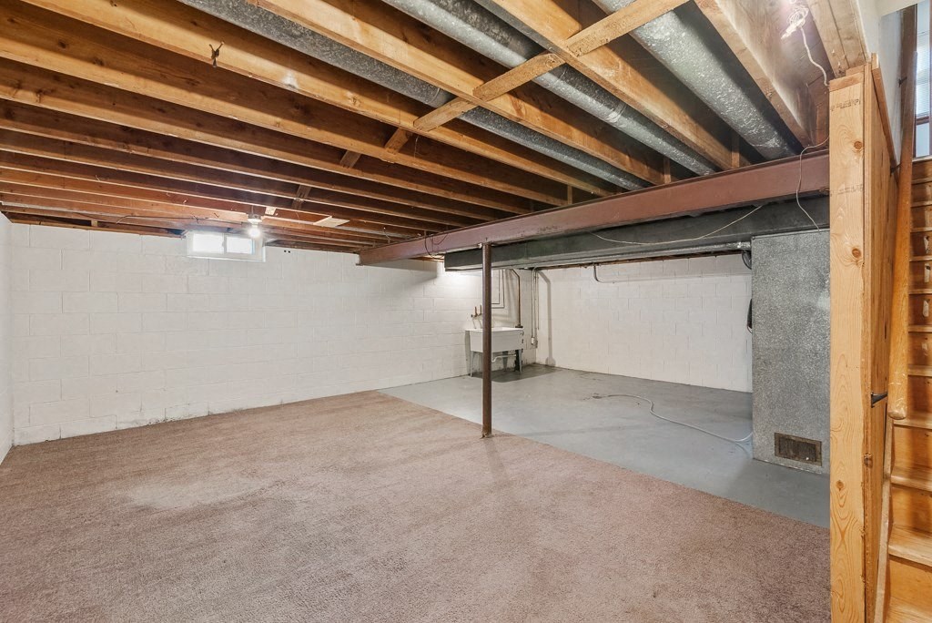 the basement of a building with a concrete floor and exposed wooden beams