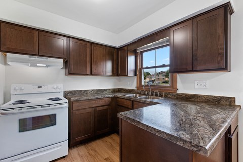 an updated kitchen with granite counter tops and wooden cabinets