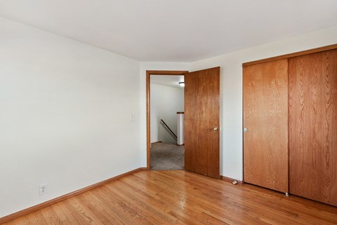 a living room with wood floors and a door to a hallway