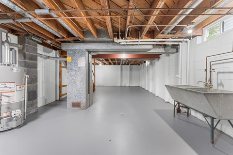 A spacious unfinished room with a concrete floor and exposed ceiling structure.