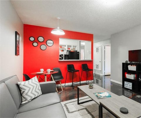 a living room with a red accent wall and a gray couch