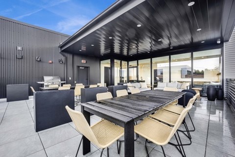 A modern outdoor dining area with a long table and chairs.