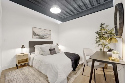 A bedroom with a bed, a chair, a table, and a painting on the wall.