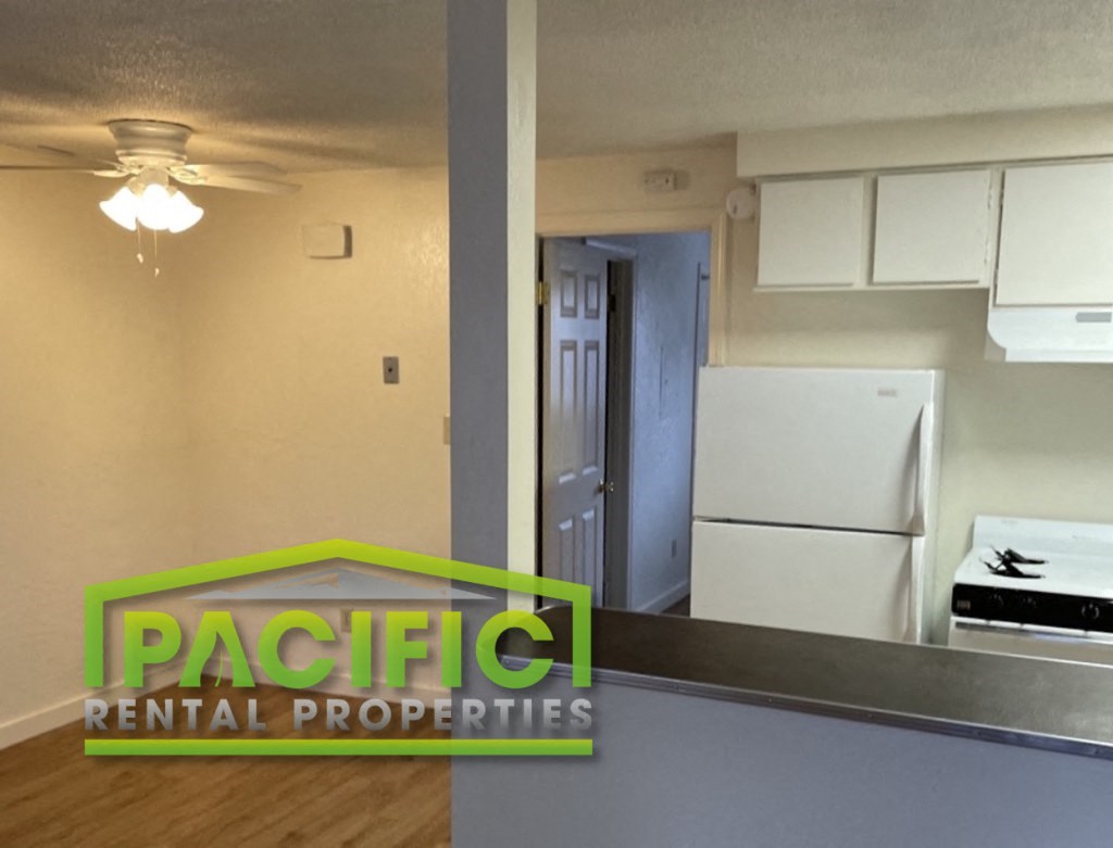 a kitchen and living room with a refrigerator and a ceiling fan