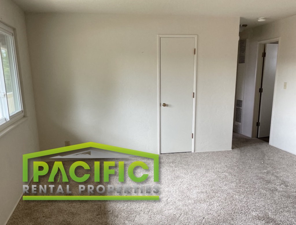 an empty room in a rental house with a pacific rental logo on the floor