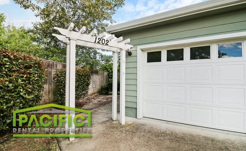 a white garage door in front of a green house