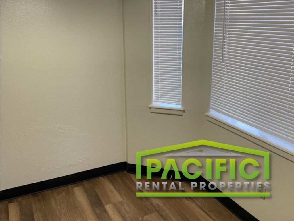 a corner of a room with two windows and a pacific rental properties sign