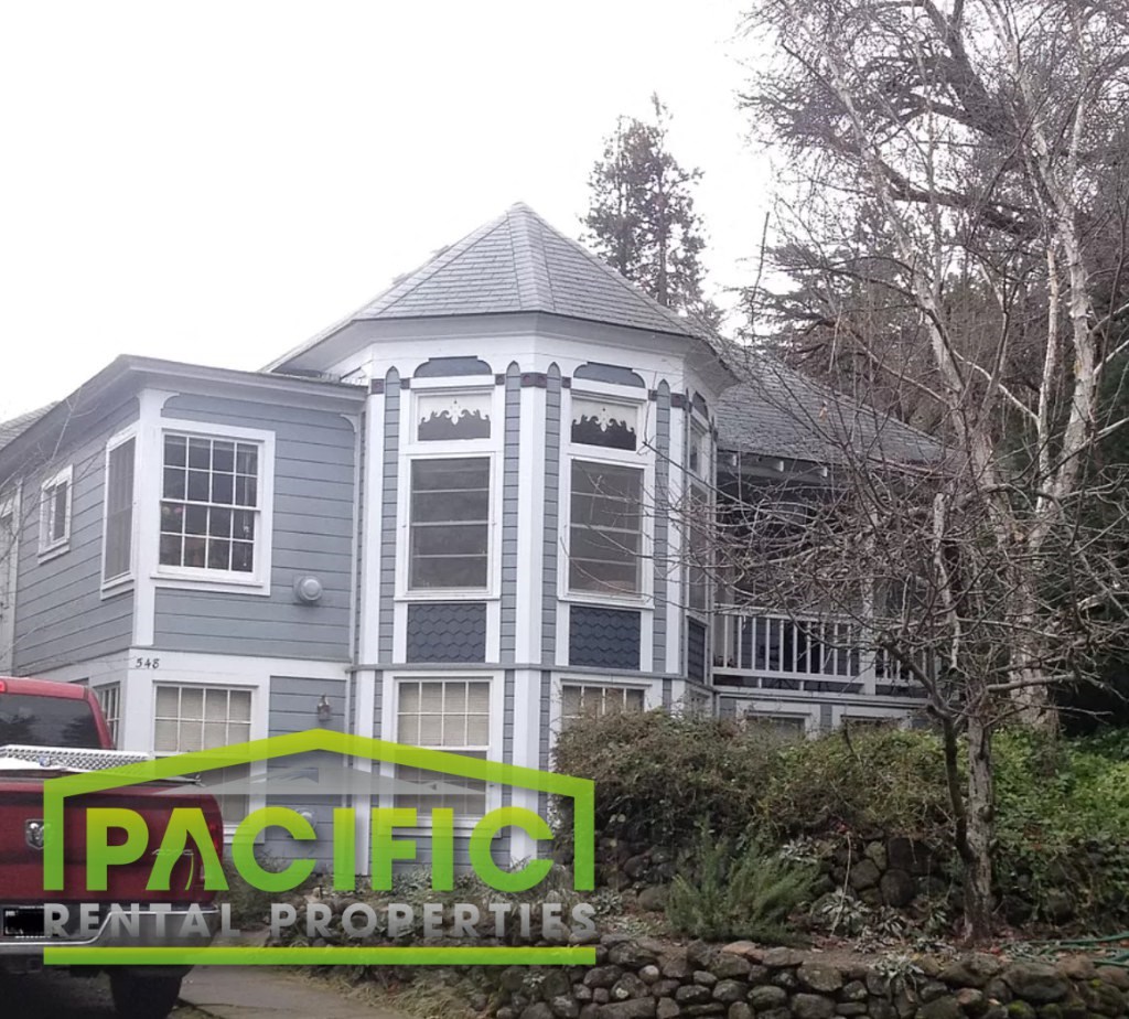 a gray house with a gray roof and a sign for pacific rental properties