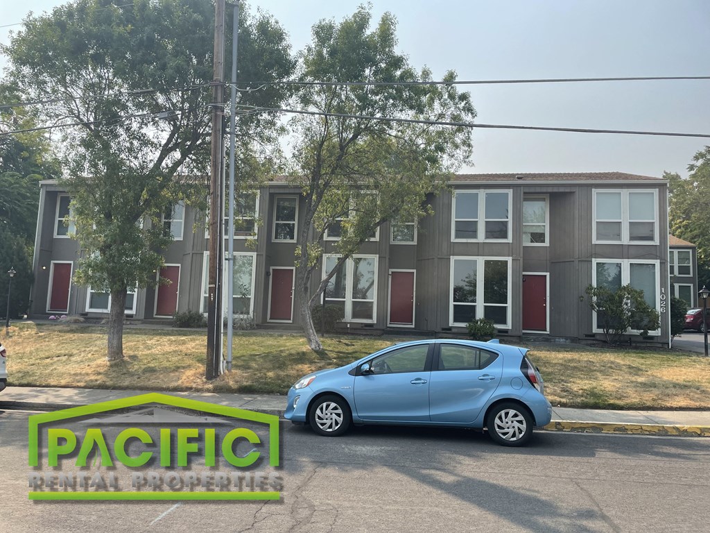 a blue car parked in front of an apartment building
