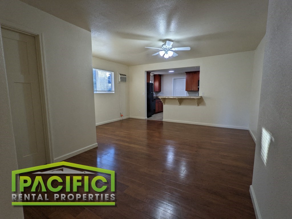 the living room and kitchen of a renovated house with wood floors and a ceiling fan