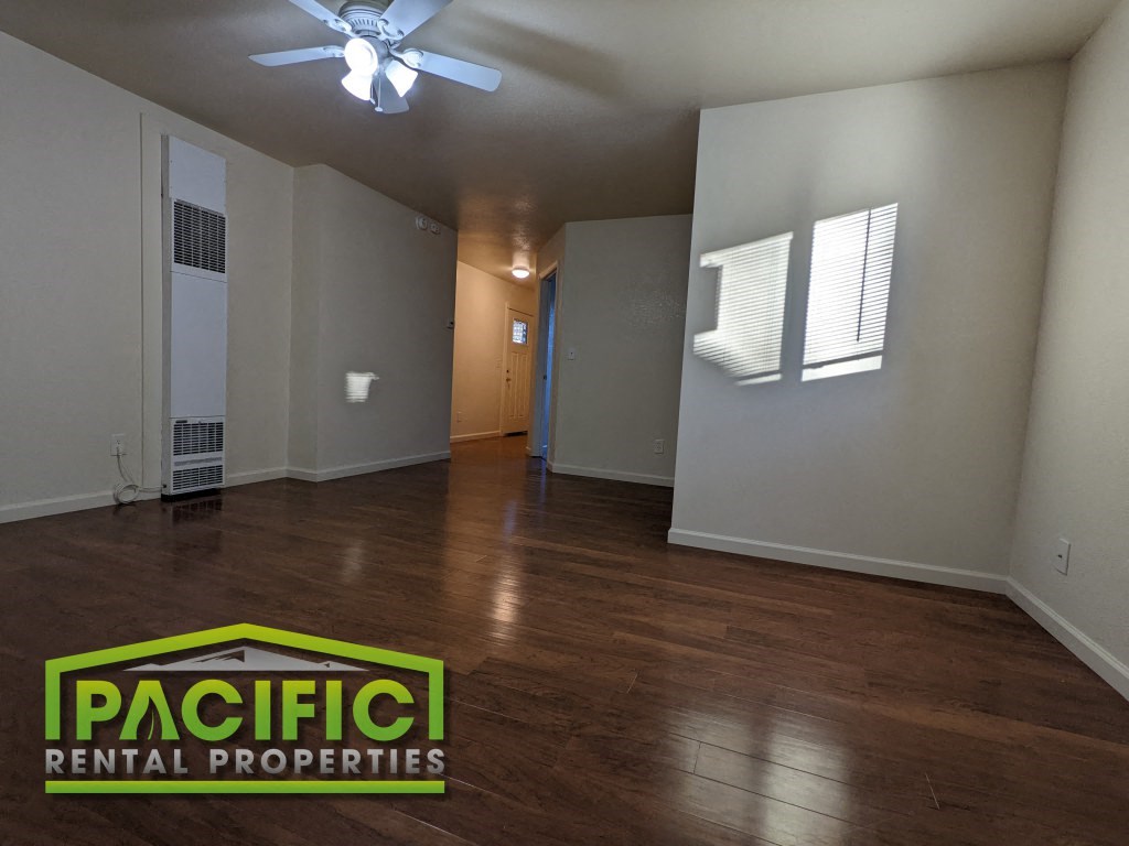 an empty living room with wood floors and a ceiling fan