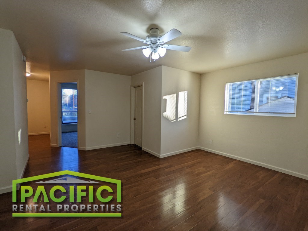 the living room and dining room of an empty house with a ceiling fan