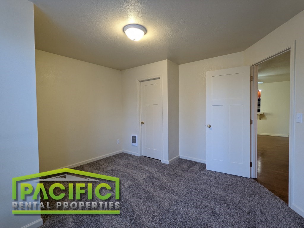 the spacious living room of a manufactured home with carpet and a door to the bathroom